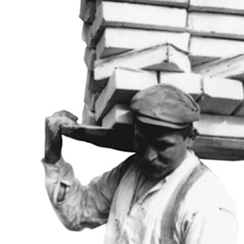 Arbeiter trägt  Ziegelsteine auf der Schulter
